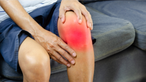 A close-up of a person holding their knee with a red highlighted area, visualizing the burning sensation of chronic joint inflammation and arthritis pain.