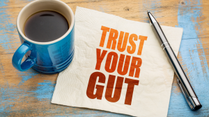 A napkin on a wooden table with the text "Trust Your Gut," illustrating the powerful connection between mental intuition and digestive health.