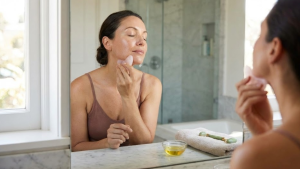 Woman performing a gua sha lymphatic drainage massage on her face to reduce puffiness and improve circulation.